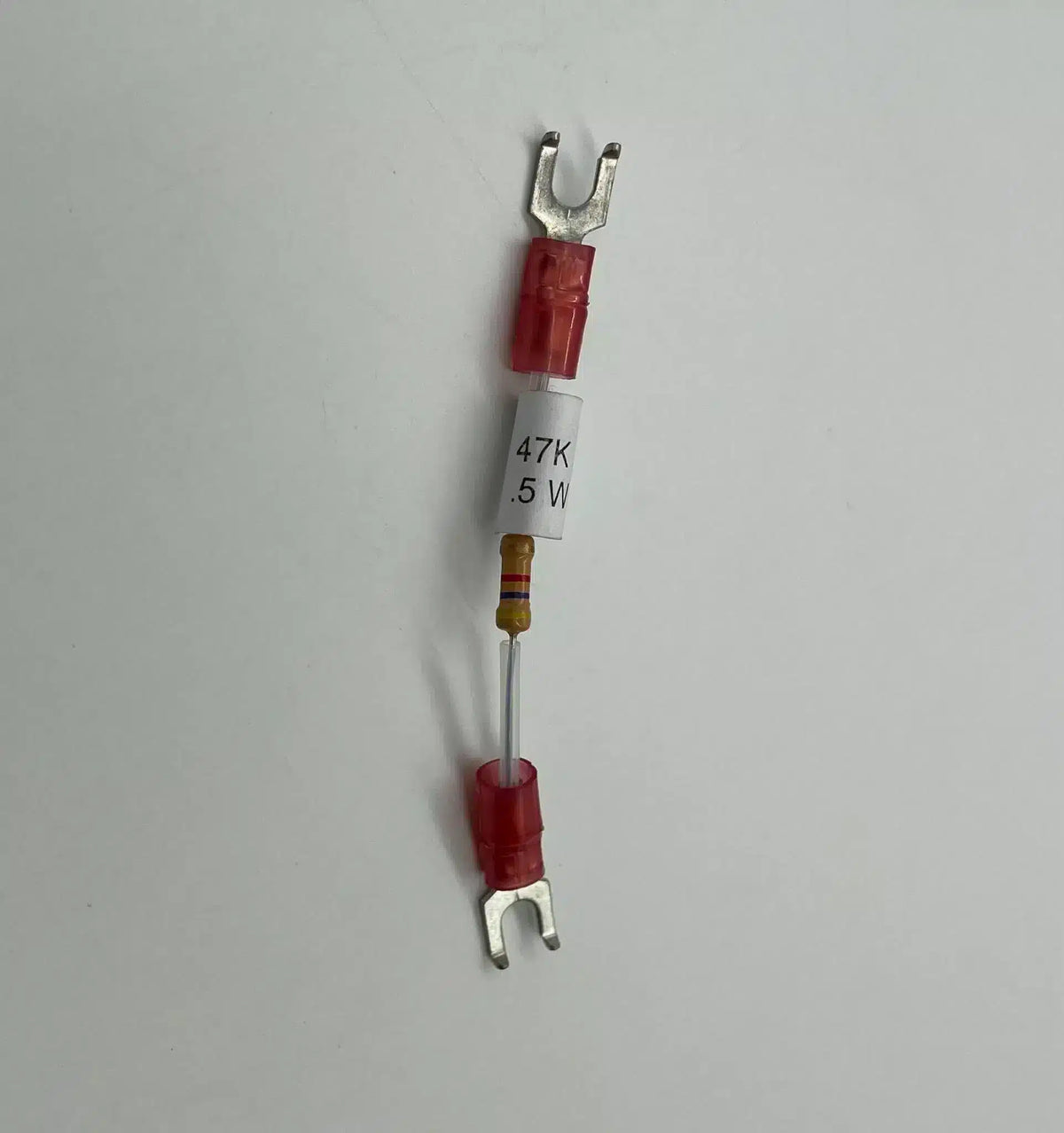 Fuse with red housing and metal terminals on a gray background